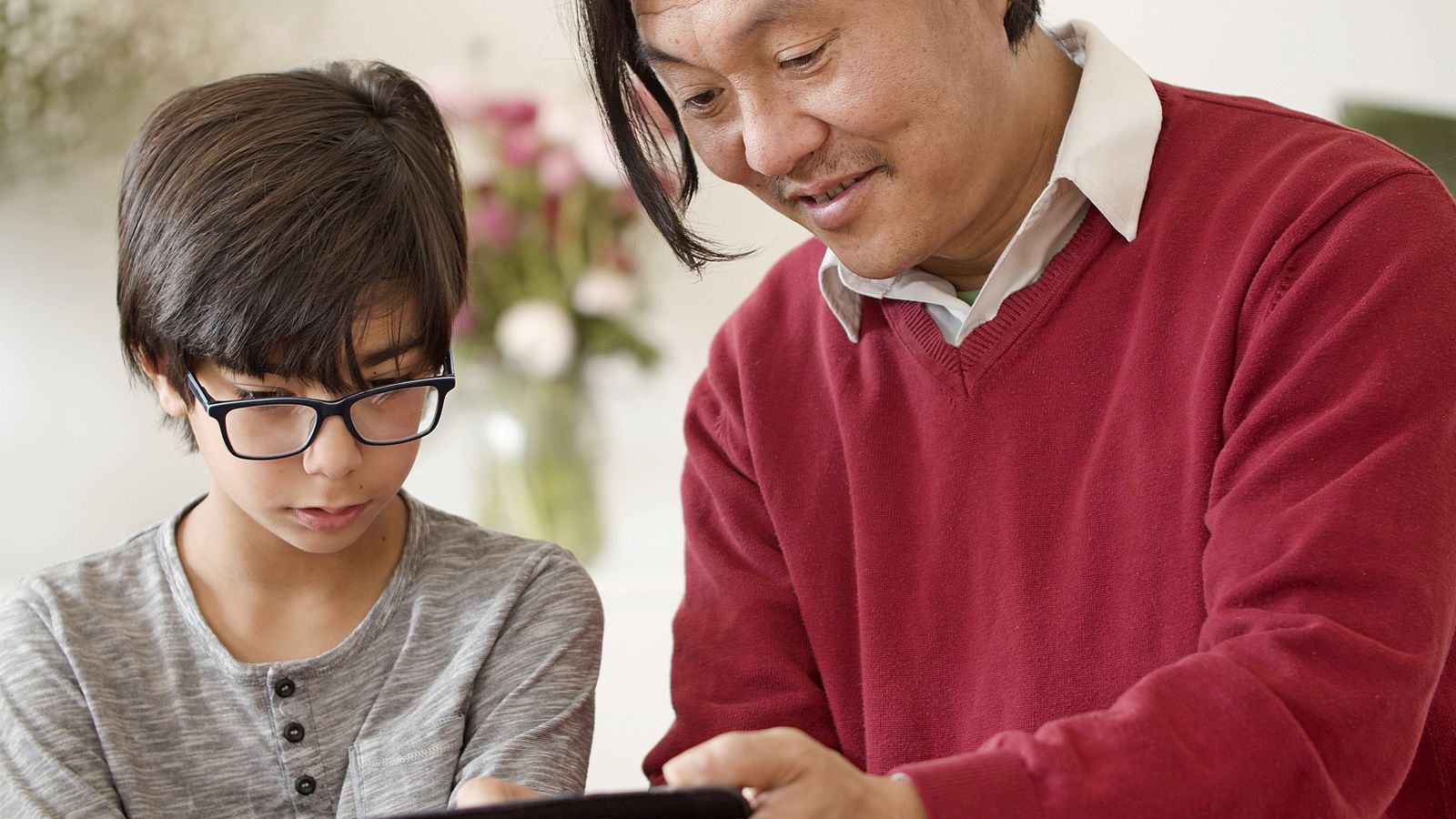 Ein Vater begleitet ein Kind ruhig bei der Nutzung eines Tablets