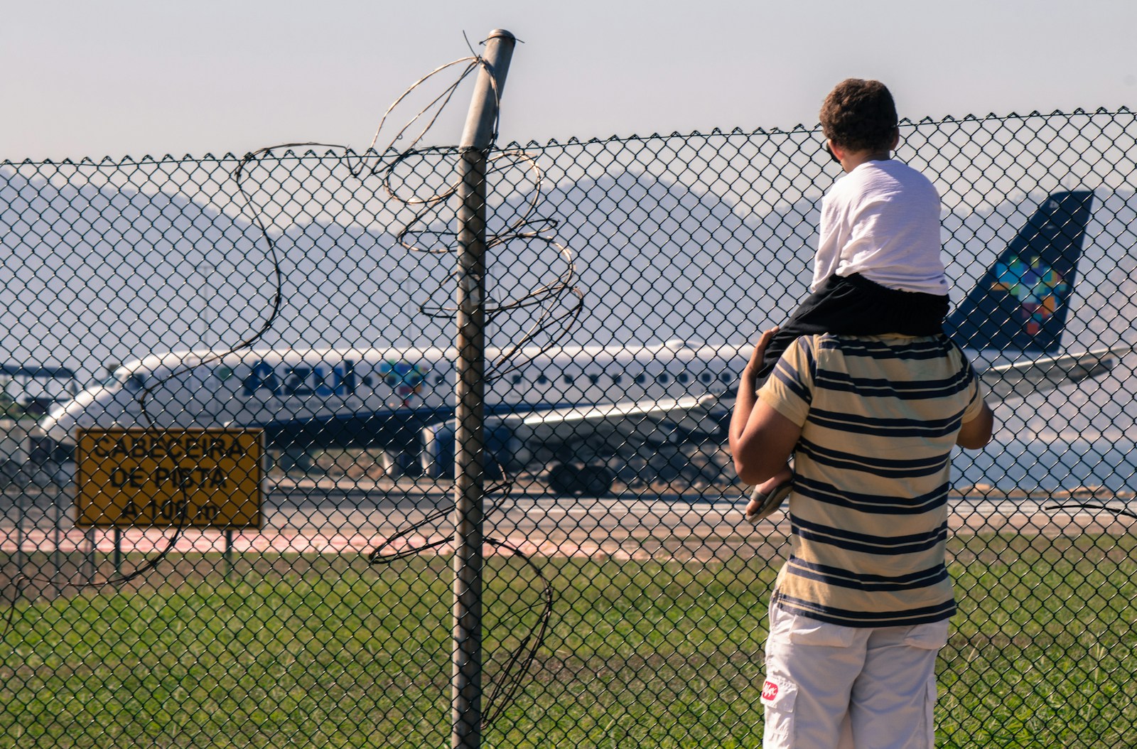 Ein Elternteil mit Kind beobachtet ein Flugzeug am Flughafen
