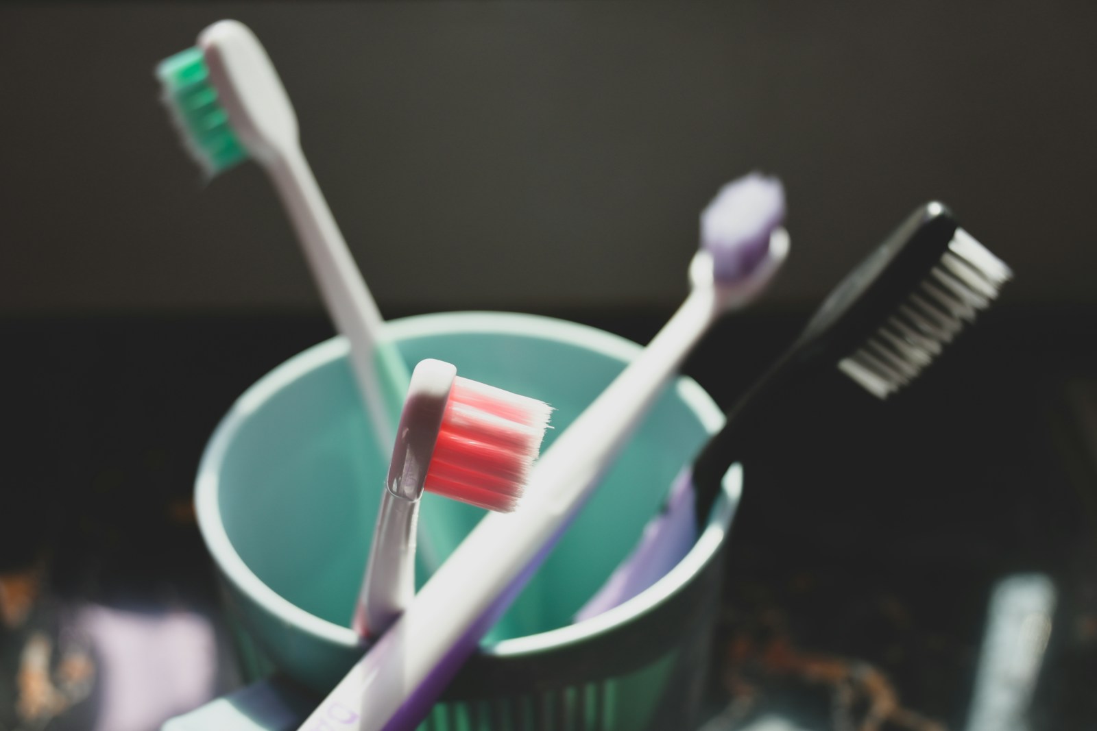 Vier Zahnbürsten in einem türkisfarbenen Becher – Symbolbild